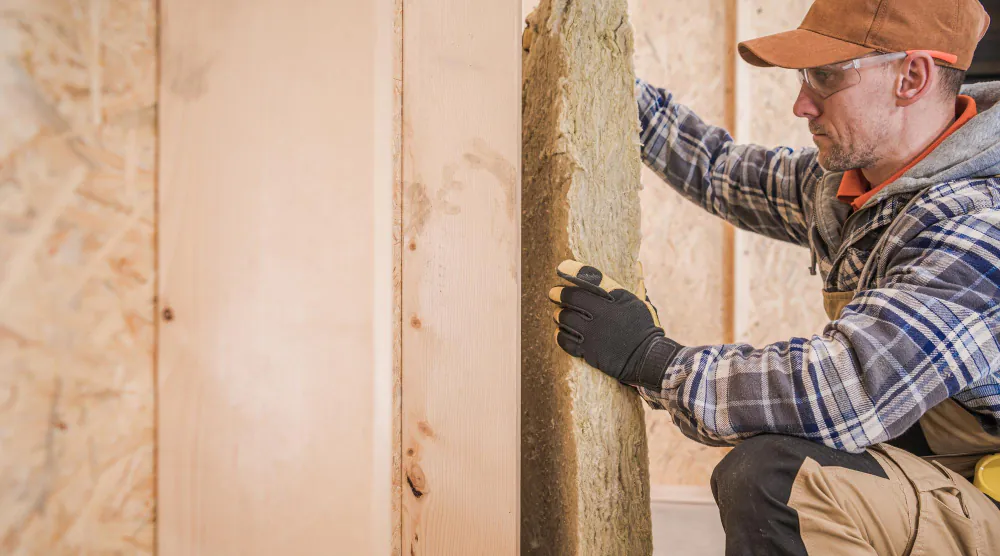 Insulation removal technician working in a timber wall frame