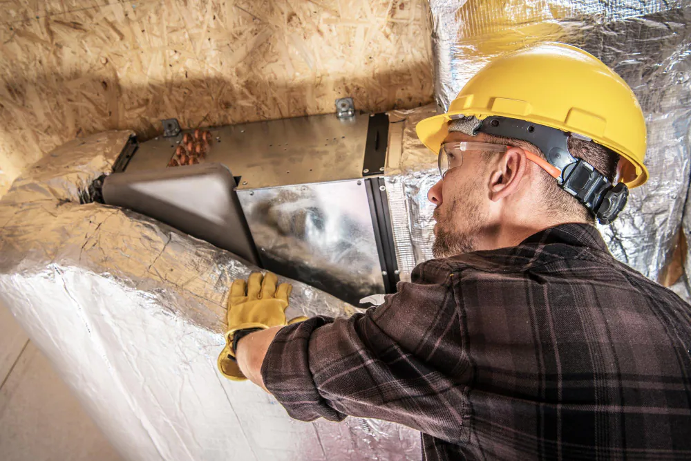 Technician inspecting a roof space and ducting