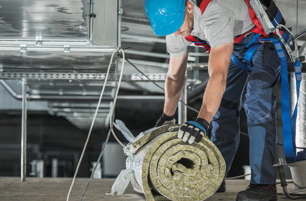 Technician rolling insulation in a commercial ceiling