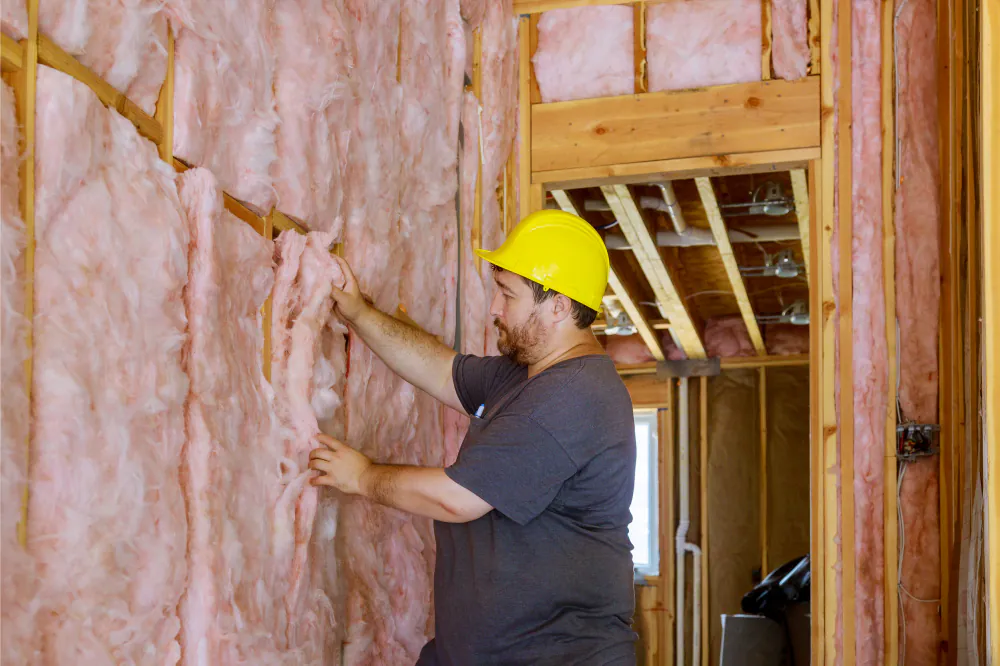 Pink wall batts being removed from a timber frame